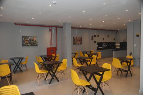 a dining room with tables and yellow chairs at Unity Hotel - Paulista - SP in São Paulo