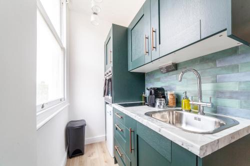 a kitchen with blue cabinets and a sink at Arte Stays Serviced Apartments Premium Studios, Finsbury Park in London