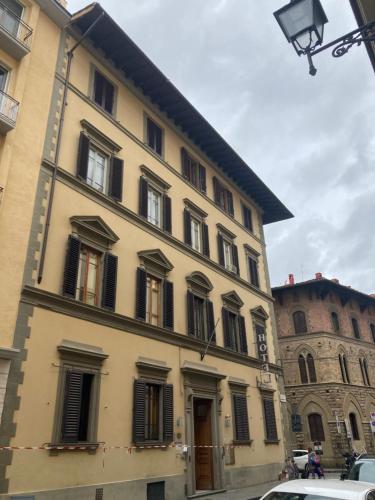 a large yellow building with black shuttered windows at Hotel Cimabue in Florence