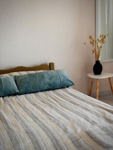 a bed with a blue pillow and a vase on a table at Sunlight apartment in Nea Peramos