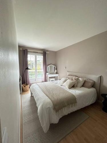 ein weißes Schlafzimmer mit einem großen Bett und einem Fenster in der Unterkunft Appartement spacieux 6 personnes in Magny-les-Hameaux