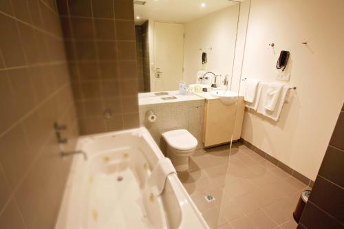 uma casa de banho com uma banheira, um WC e um lavatório. em Golden Pebble Hotel em Wantirna