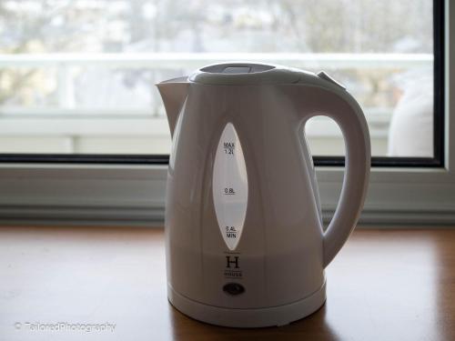 a white electric kettle sitting on a table next to a window at Studiohuoneisto Ainonkatu AC, WiFi, balcony in Lappeenranta