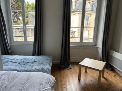 a room with a bed and a table and windows at Maison centre historique in Bayeux