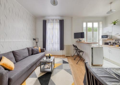 Il comprend un salon avec un canapé gris et une cuisine. dans l'établissement Calme, Paris, Métro 10 min, RER B 7 min, Orly - Genius, à Arcueil