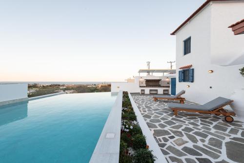 a swimming pool with two lounge chairs on the side of a house at Kalathos Square luxury suites in Kalathos