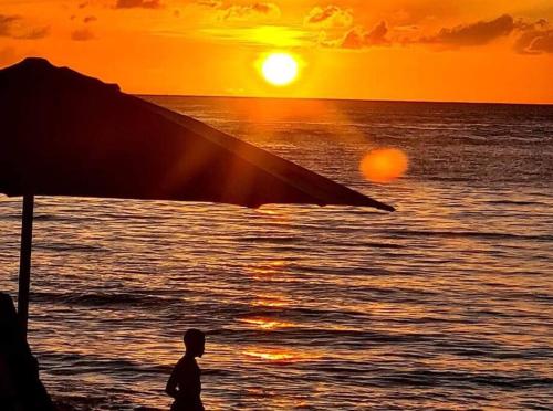 une personne se promenant sur la plage au coucher du soleil dans l'établissement Ottie-Newly Renovated, 5 min from beach, à Saint James