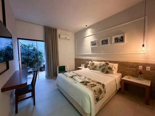 a bedroom with a bed and a desk and a television at Passagem Concept Hotel e Spa in Cabo Frio