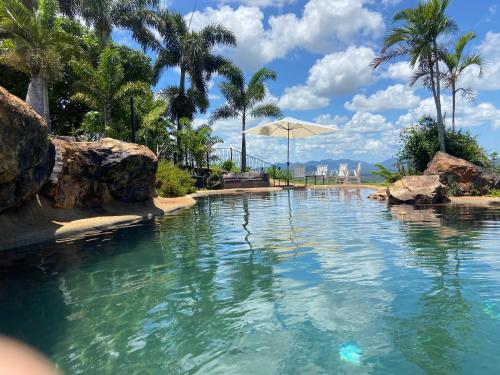 a swimming pool with an umbrella and palm trees at The Lookout Chalet luxury getaway retreat in Farnborough