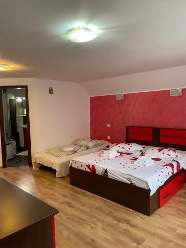 a bedroom with two beds and a red wall at Casa Elegant in Moieciu de Jos