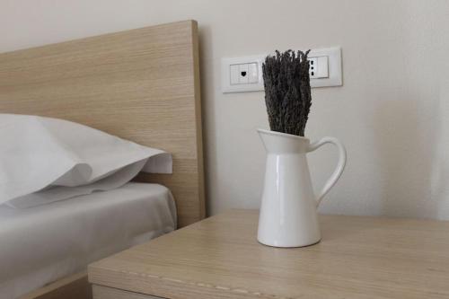 a white vase sitting on a table next to a bed at Lavandula Ring in Tirana