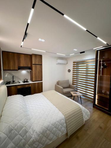 a bedroom with a large white bed and a kitchen at Aria's Apartments in Elbasan