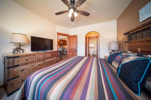 a bedroom with a bed and a flat screen tv at Cozens Pointe Building I Unit I201 by Stay Winter Park in Fraser