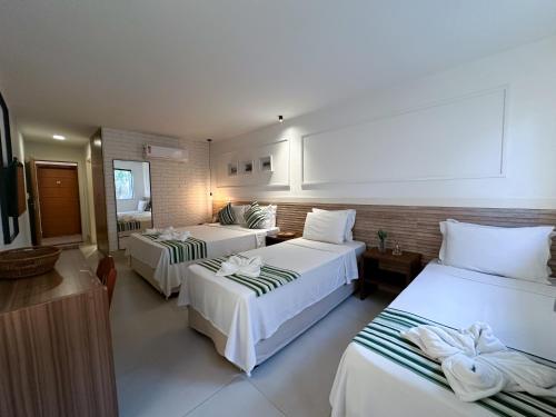 a hotel room with two beds and a television at Passagem Concept Hotel e Spa in Cabo Frio