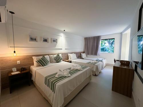 a hotel room with two beds and a television at Passagem Concept Hotel e Spa in Cabo Frio