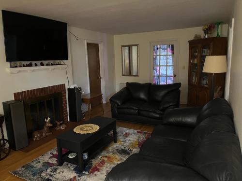 a living room with a black leather couch and a fireplace at A cozy nest in Delmar 