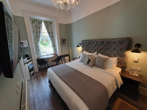 a bedroom with a large bed with a chandelier at Highlander House B&B in Rothesay
