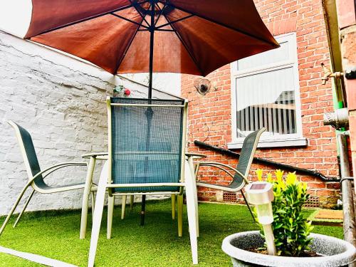 een patio met een tafel en stoelen en een parasol bij 3 BDR House ,Free Parking ,Netflix ,WiFi, Near City Centre and Stockport in Manchester