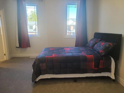 een bed in een kamer met 2 ramen bij Elegant 4 BR 3.5 Bath Oasis: Mins frm Coburg Beach in Cobourg