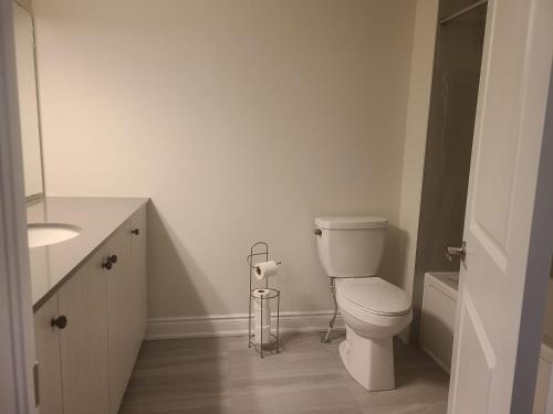 a white bathroom with a toilet and a sink at Elegant 4 BR 3.5 Bath Oasis: Mins frm Coburg Beach in Cobourg