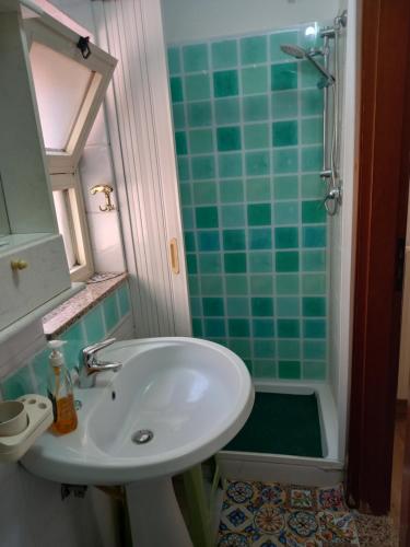 La salle de bains est pourvue d'un lavabo et d'une douche carrelée de couleur verte. dans l'établissement Casa turistica Santa Lucia 25, à Regalbuto