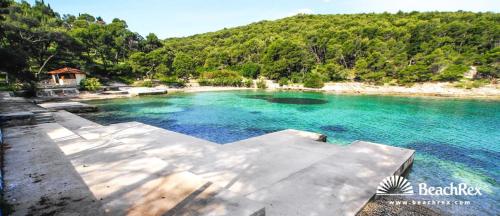 a large pool of blue water next to a beach at Holiday house Mila in Postira