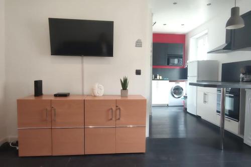 une cuisine avec un meuble marron avec une télévision au mur dans l'établissement Charmant cocon au cœur de Reims, à Reims