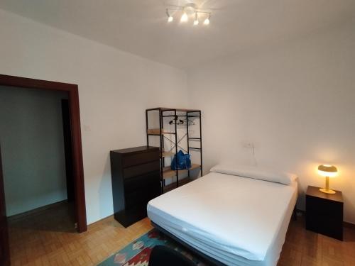 una camera con letto, cassettiera e lampada di Apartamento en Silla del Rey a Oviedo