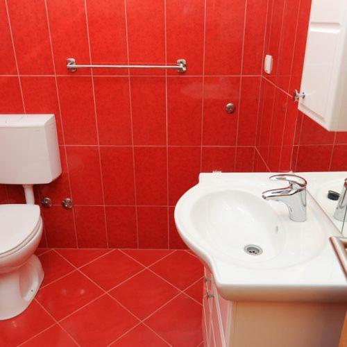 a red bathroom with a toilet and a sink at Apartmani Ivo in Podstrana