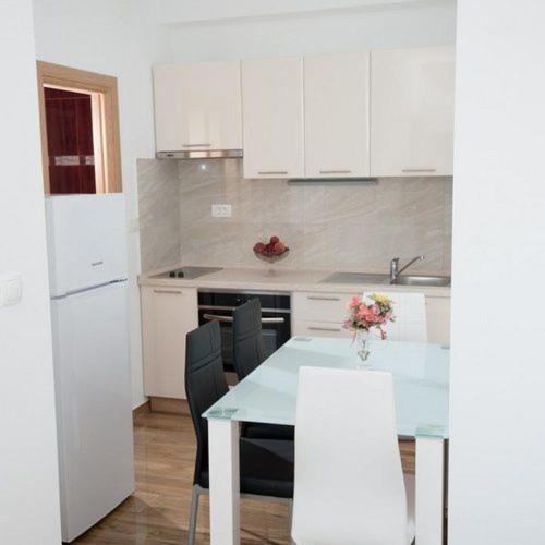 a kitchen with a table and chairs and white cabinets at Apartmani Ivo in Podstrana