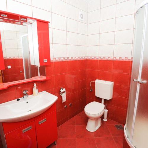 a red bathroom with a toilet and a sink at Apartmani Ivo in Podstrana