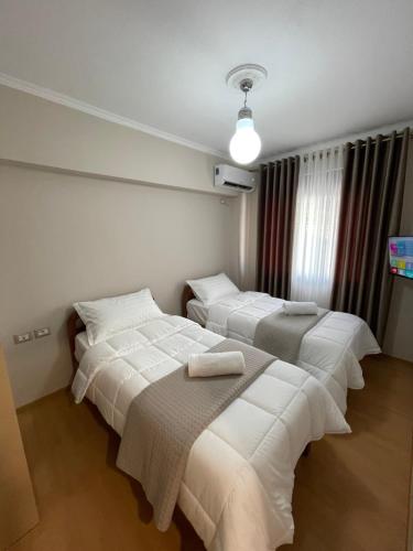 3 Betten in einem Zimmer mit weißer Bettwäsche in der Unterkunft Andi's Apartment 2 in Gjirokastër