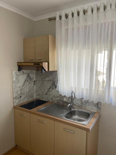 eine kleine Küche mit einem Waschbecken und einem Fenster in der Unterkunft Andi's Apartment 2 in Gjirokastër