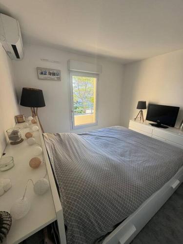 une chambre blanche avec un lit et une télévision dans l'établissement Spacieux T2 - Grande terrasse, à Fréjus