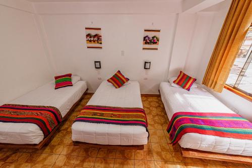 Pokój z dwoma łóżkami z kolorowymi kocami na nich w obiekcie Sacred Inka House w Machu Picchu