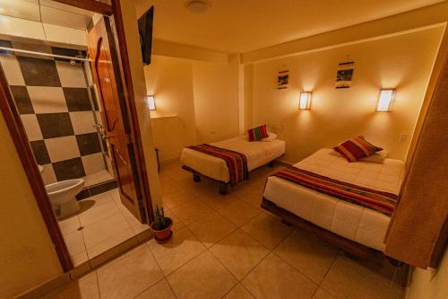a hotel room with two beds and a bathroom at Sacred Inka House in Machu Picchu