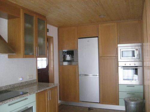 a kitchen with wooden cabinets and a white refrigerator at Casa Campo do Telhado in Caldelas