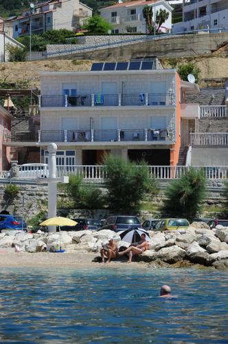 two people laying on the beach in the water at Apartmani Ivo in Podstrana