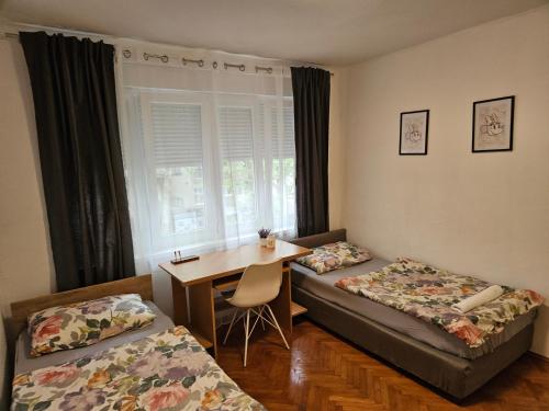een kamer met 2 bedden, een bureau en een tafel bij Apartment Mia in Mostar