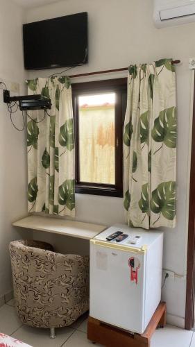 a small refrigerator in a room with a window at Suítes Para Casal in Bertioga