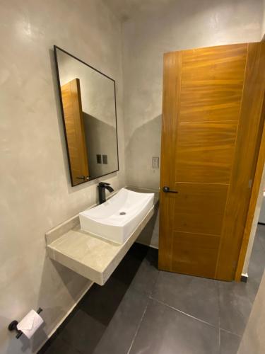 W łazience znajduje się biała umywalka i lustro. w obiekcie Coco Live Suites w mieście Playa del Carmen