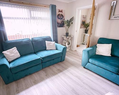 a living room with two blue couches and a window at The Serene Stays - 3 Bed Home in Oldham Manchester in Oldham