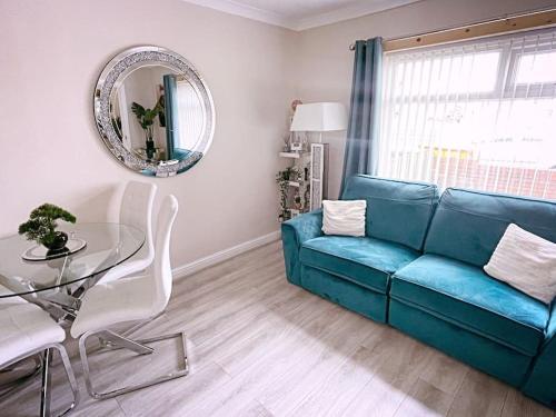 a living room with a blue couch and a glass table at The Serene Stays - 3 Bed Home in Oldham Manchester in Oldham