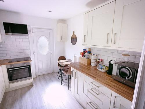 a kitchen with white cabinets and a counter with a microwave at The Serene Stays - 3 Bed Home in Oldham Manchester in Oldham