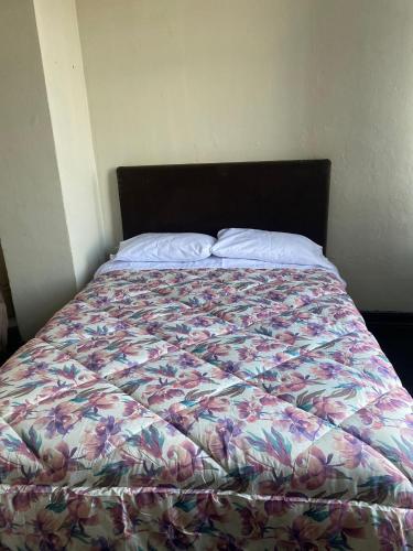 a bed with a floral comforter in a bedroom at Habitación en Centro Histórico in Lima