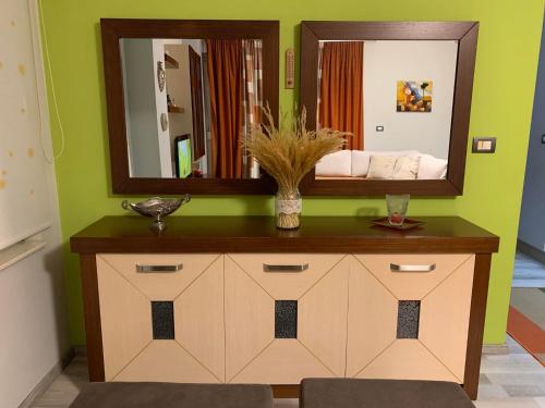 a bathroom with a vanity with a mirror on a green wall at Downtown Apartment in Korçë