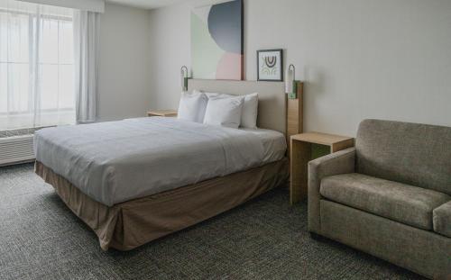 a hotel room with a bed and a chair at High Plains Hotel at Denver International Airport in Denver