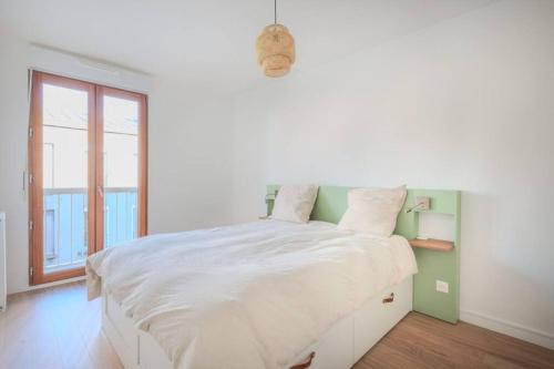 una camera bianca con un grande letto con finestra di Charmant appartement avec balcon à St-Denis a Saint-Denis