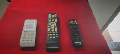 three remote controls sitting on top of a red table at Suítes Para Casal in Bertioga