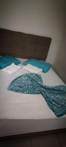 a bed with blue pillows and a blanket on it at Suítes Para Casal in Bertioga